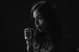 Mujer cantando frente al microfono en fondo negro