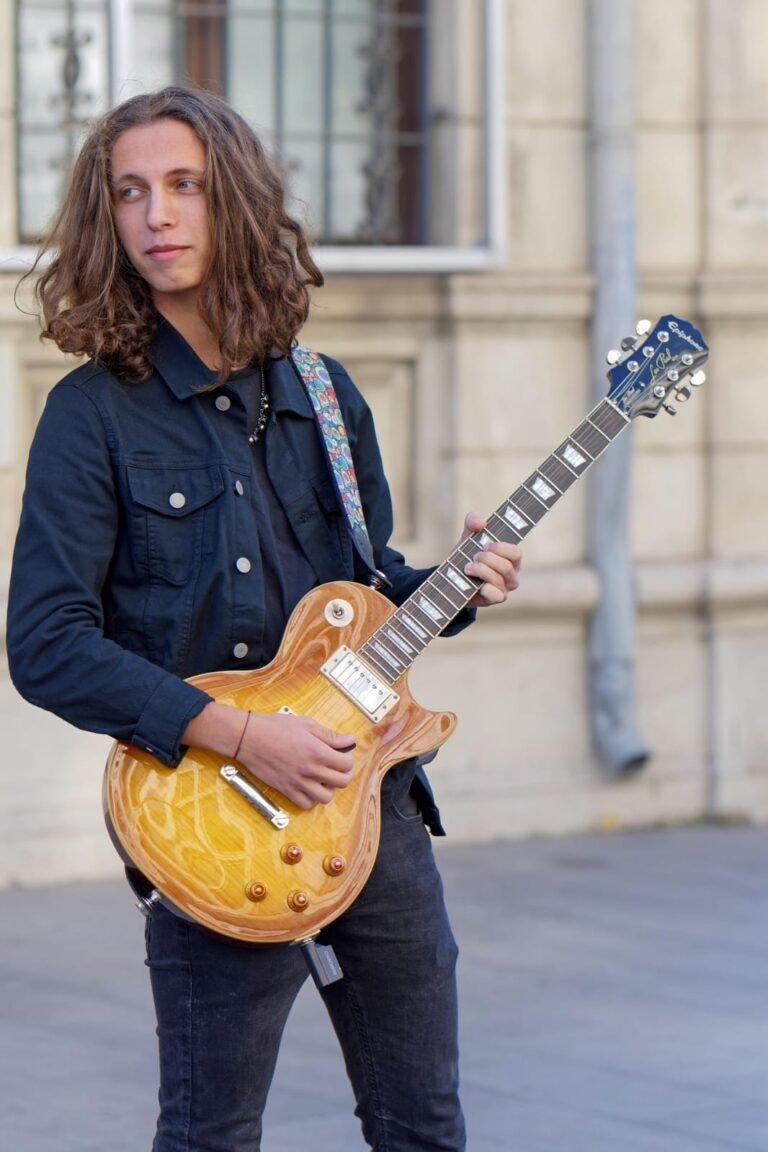 Joven caminando en la calle con guitarra electrica