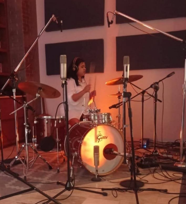 mujer tocando la bateria con audifonos puestos