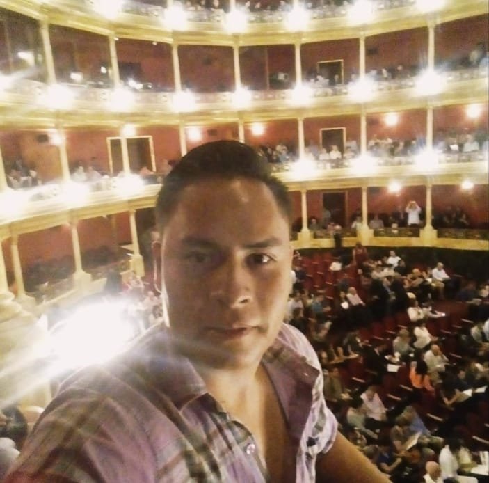 Hombre en primer plano con butacas de teatro en segundo plano