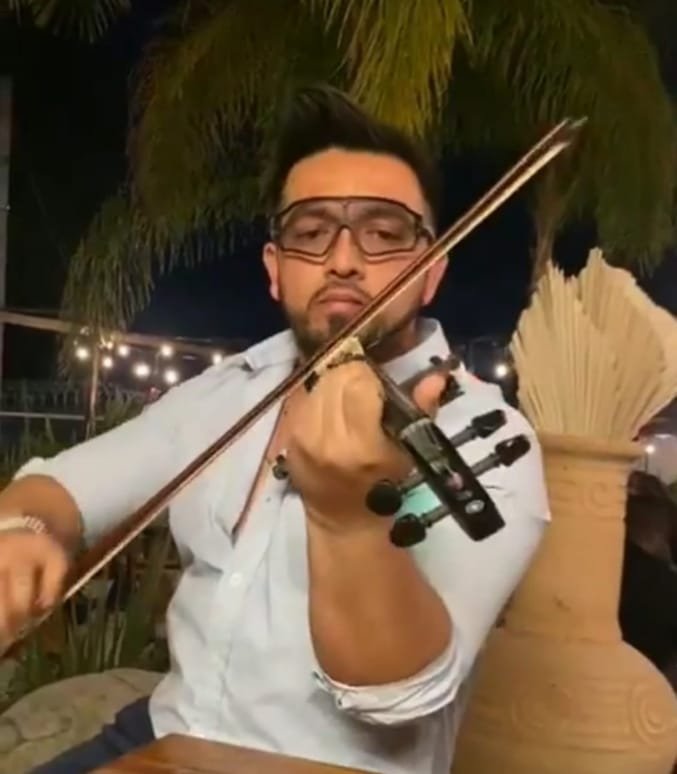 Hombre de camisa blanca y lentes oscuros tocando el violin