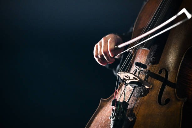 Mano de hombre dando una arcada a violoncello en fondo negro